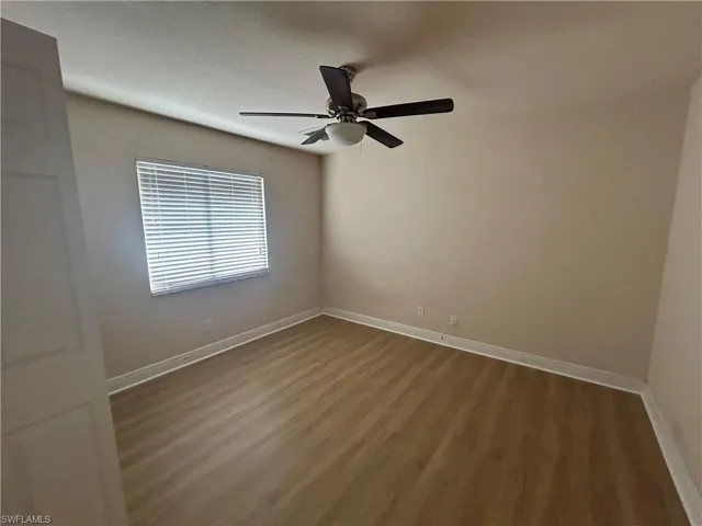 Spare room with dark wood-type flooring and ceiling fan
