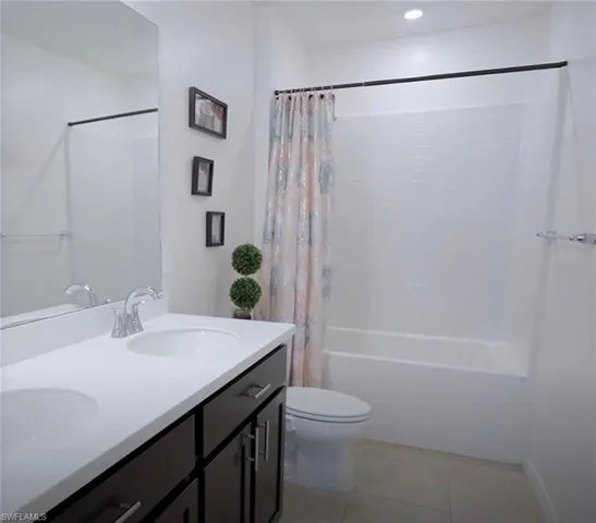 Full bathroom with tile patterned flooring, vanity, toilet, and shower / bath combination with curtain