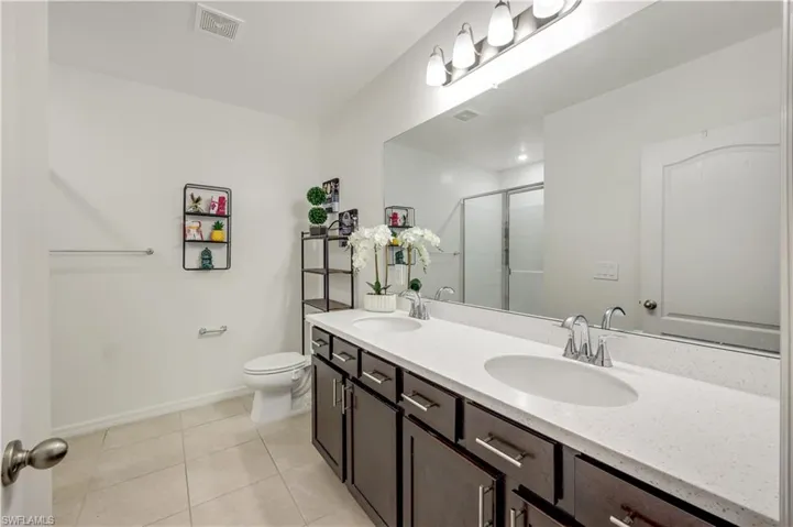 Bathroom featuring walk in shower, vanity, toilet, and tile patterned floors