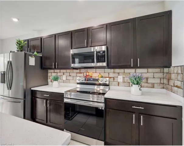 Kitchen with stainless steel appliances, dark brown cabinetry, and tasteful backsplash