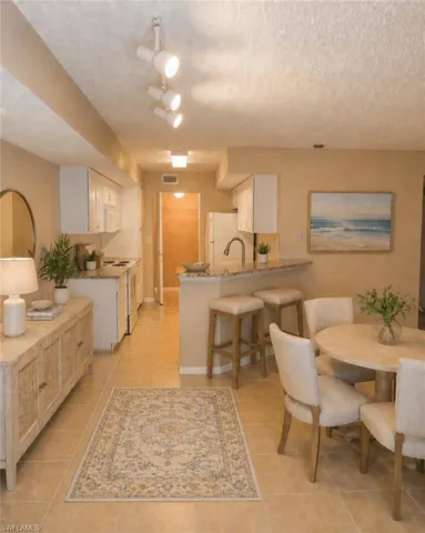 Open-concept kitchen and dining area featuring tile flooring, white cabinetry, a breakfast bar with seating, and track lighting