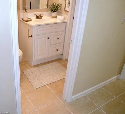 Bathroom featuring a white vanity with a single basin, light-toned countertop, and bronze-finish faucet