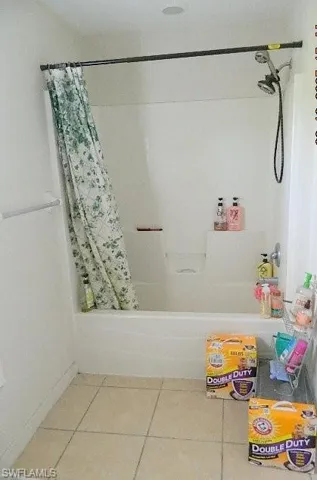 Full bathroom with shower / tub combo with curtain and tile patterned flooring