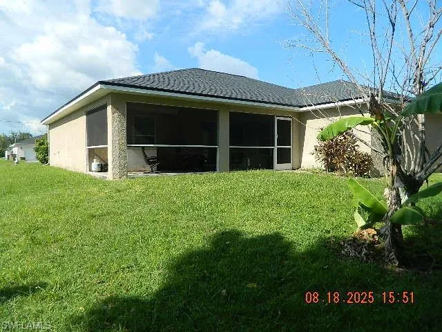 Rear view of property featuring stucco siding, a yard, and a sunroom
