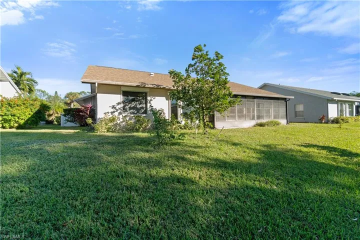 Back of property with a lawn and a sunroom