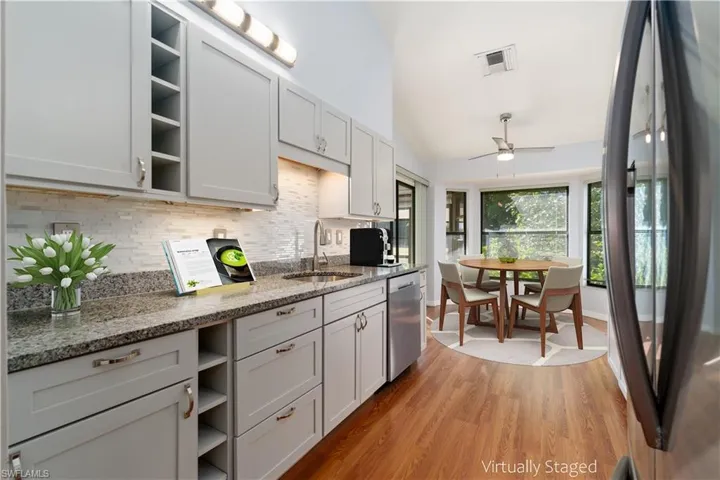 Newly Remodeled Kitchen with VIRTUALLY STAGED Kitchen eat-In Area. stone counters, light hardwood / wood-style flooring, vaulted ceiling, and new stainless appliances.