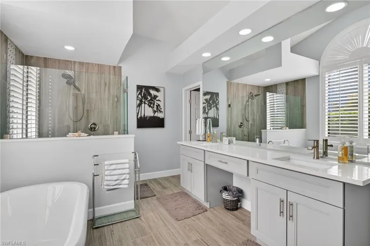 Updated primary bathroom has dual sinks, tub and shower as well as large closets