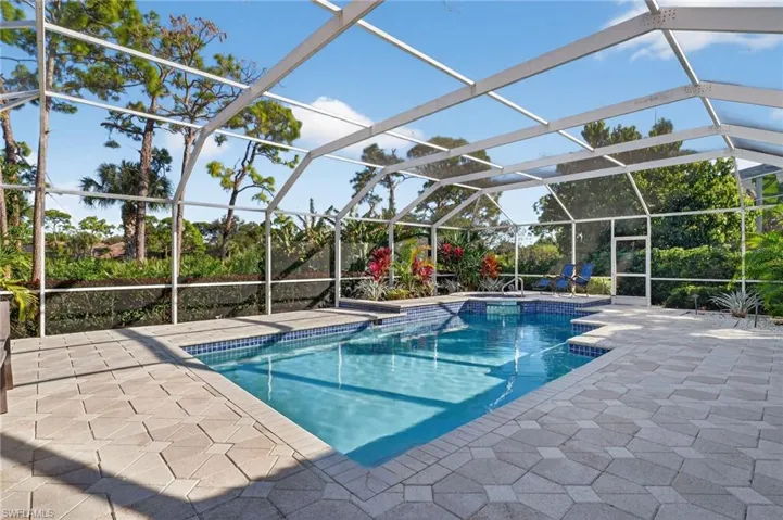 A stunning pool and hot tub with pavers on your oversized screened lanai
