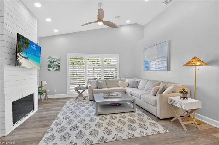 This lovely family room contains a fireplace, TV and a shiplap accent wall right by the kitchen area