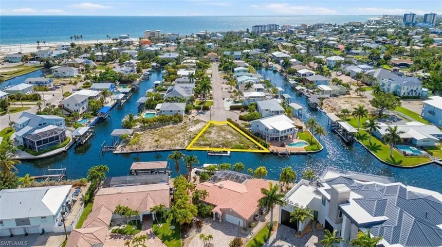 Vacant waterfront land parcel bordered by canals on two sides, featuring direct canal access, a triangular lot shape, and proximity to the open water - Virtually Edited Image