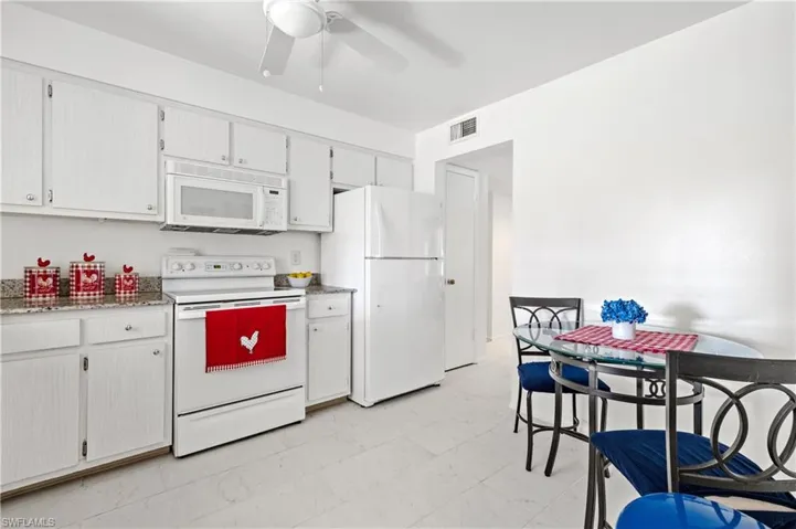 Kitchen featuring white appliances, ceiling fan, white cabinets, and light floors