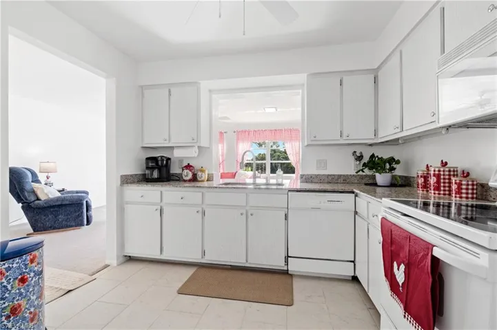Kitchen with white appliances, white cabinets, and ceiling fan