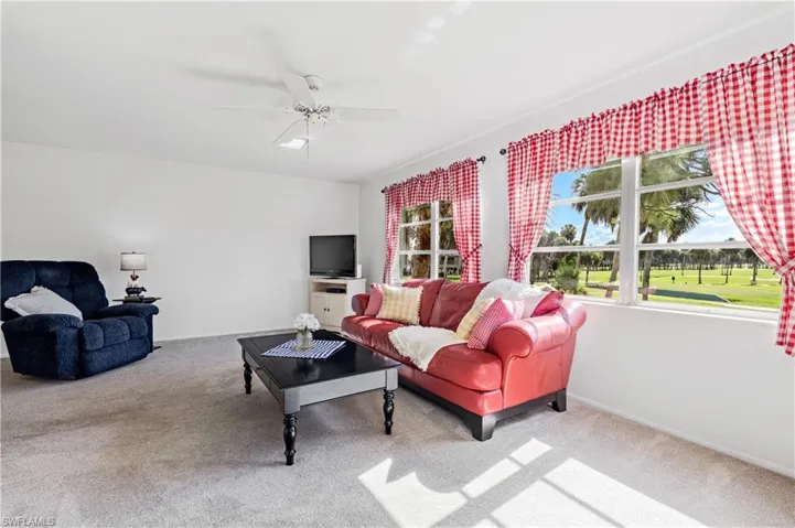 Carpeted living room featuring a ceiling fan