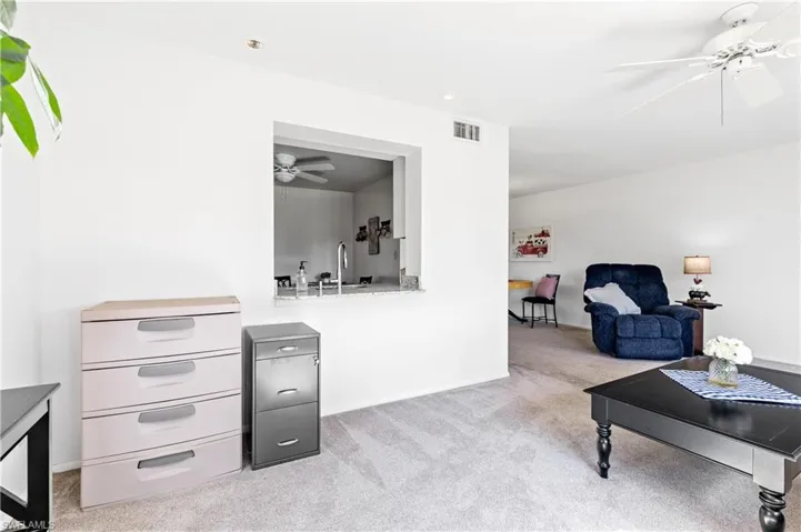Living room with a ceiling fan and light carpet