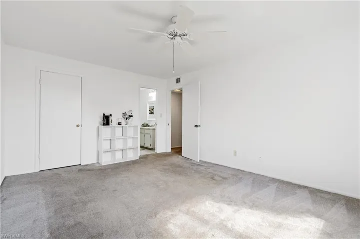 Unfurnished bedroom with light carpet, connected bathroom, and a ceiling fan