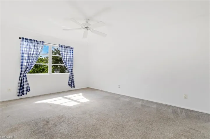 Empty room featuring carpet flooring and a ceiling fan