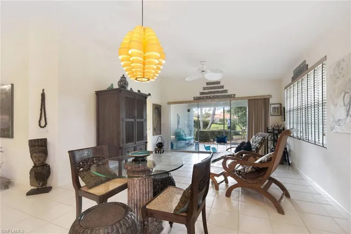 Dining room featuring ceiling fan with notable chandelier, light tile patterned floors, and vaulted ceiling