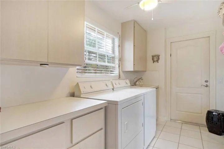 Laundry room featuring cabinets, sink, ceiling fan, independent washer and dryer, and light tile patterned flooring