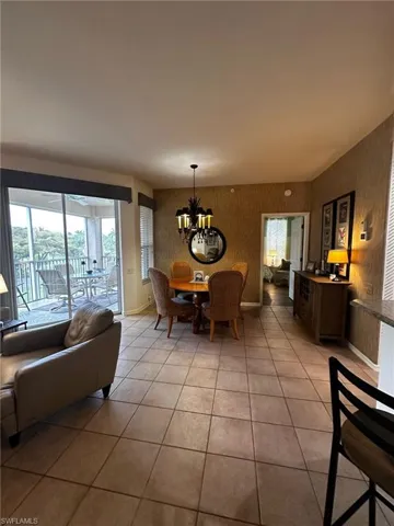 Dining room featuring baseboards, a notable chandelier, wallpapered walls, and light tile patterned flooring