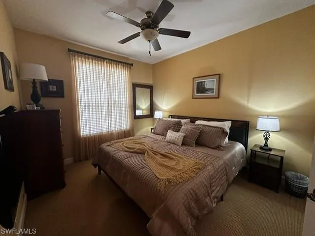 Carpeted bedroom featuring a ceiling fan and baseboards