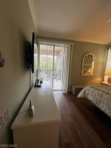 Bedroom with baseboards, wood finished floors, ornamental molding, and access to exterior