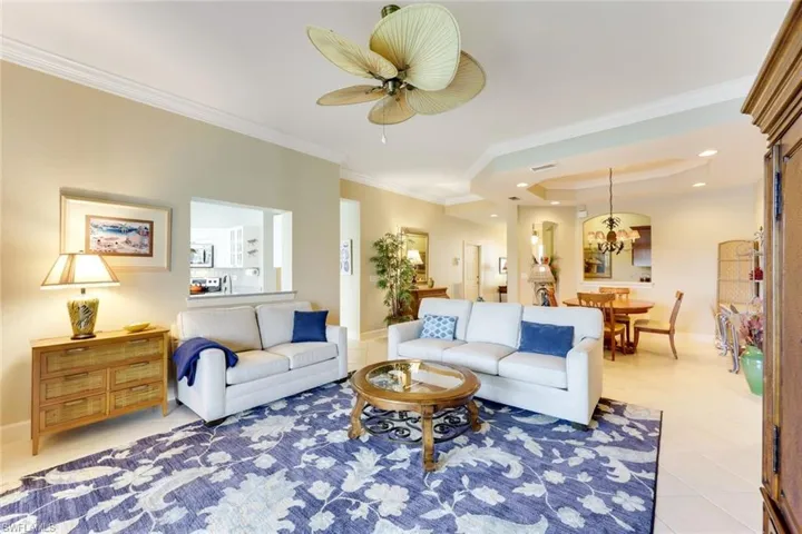 Long view of great room, coffered ceiling, pass-through to wet-bar, and front entry (back left).
