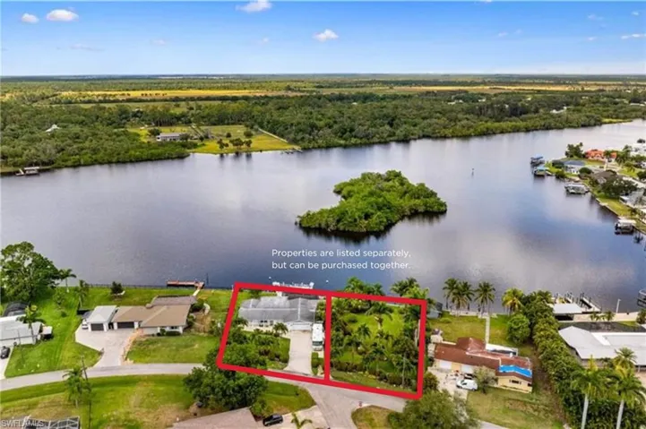 Aerial perspective of suburban area with a nearby body of water, property boundaries highlighted, and a heavily wooded area