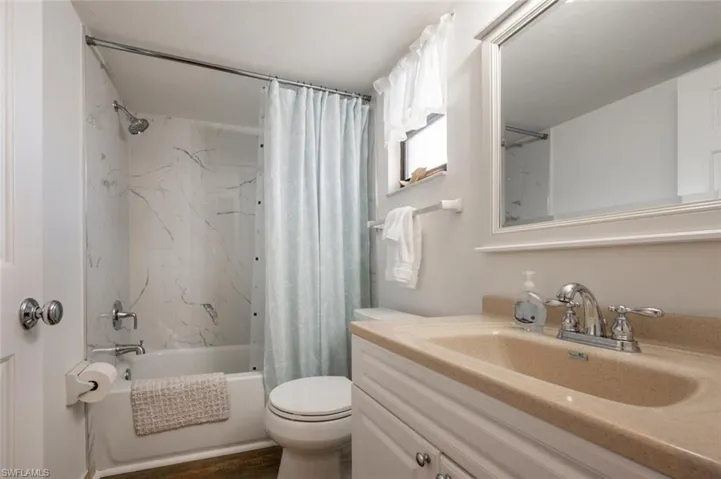 Full bathroom with vanity, toilet, hardwood / wood-style flooring, and shower / bath combo with shower curtain