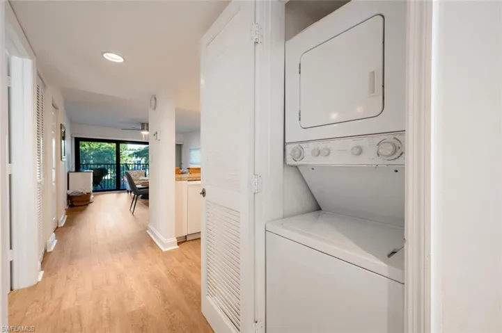 Laundry area featuring light hardwood / wood-style floors and stacked washer and dryer