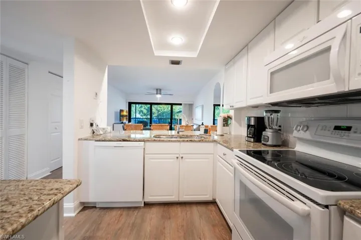 Kitchen with white appliances, sink, kitchen peninsula, light hardwood / wood-style floors, and white cabinets