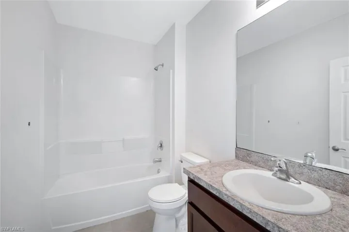 Full bathroom with vanity, tub / shower combination, tile patterned floors, and toilet