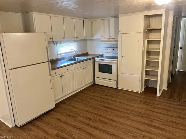 Kitchen featuring white appliances, sink, white cabinetry, and dark hardwood / wood-style flooring