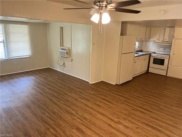 Kitchen with dark wood-type flooring, ceiling fan, sink, and white appliances