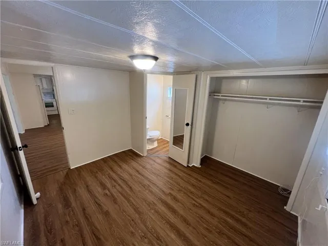 Unfurnished bedroom featuring a closet, a textured ceiling, and dark wood-type flooring