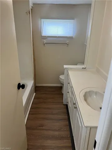 Full bathroom with shower / bath combination, hardwood / wood-style floors, toilet, and vanity