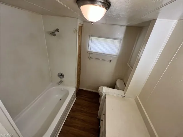 Full bathroom with vanity, wood-type flooring, shower / bath combination, and toilet