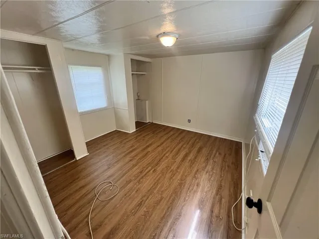 Unfurnished bedroom with multiple windows, hardwood / wood-style flooring, and multiple closets