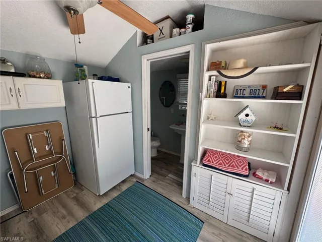 Kitchen with a textured ceiling, light hardwood / wood-style floors, vaulted ceiling, and white refrigerator
