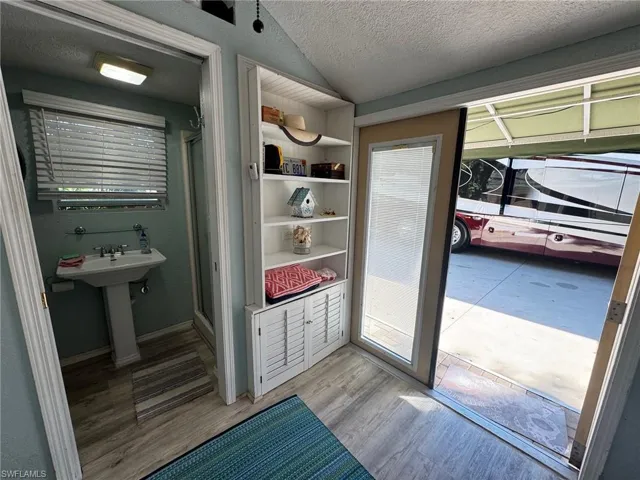 Mudroom featuring a textured ceiling, light hardwood / wood-style flooring, and lofted ceiling
