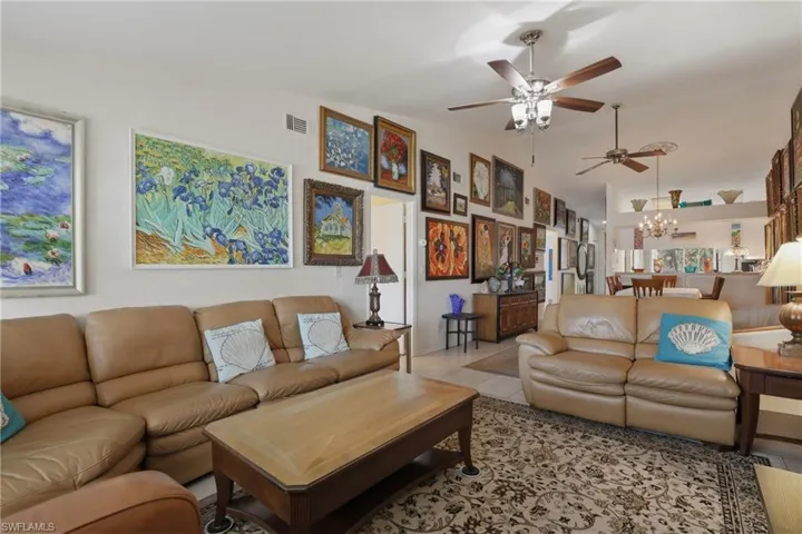 Open concept living area featuring light-toned walls and multiple ceiling fans