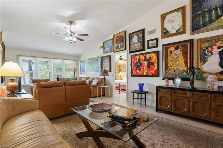Spacious living area featuring a vaulted ceiling and an array of large windows