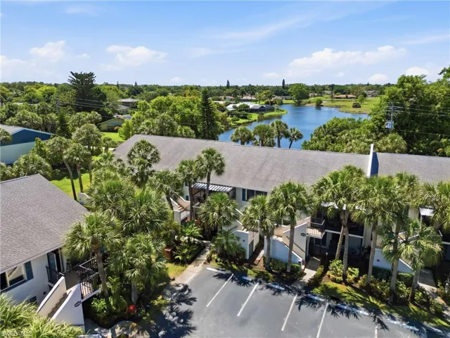 Multi-story property featuring a lake background and abundant palm trees