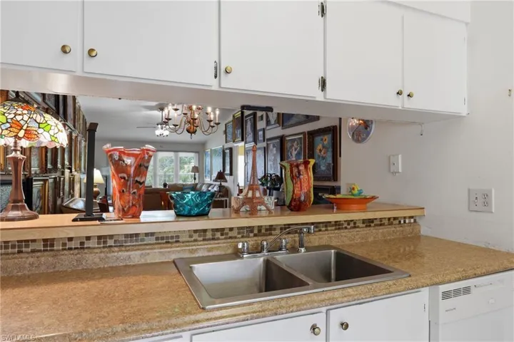 Kitchen area featuring a stainless steel double-basin sink, laminate countertops, and a mosaic tile backsplash