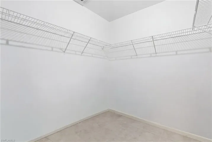 Walk-in closet featuring white wire shelving, light-toned tile flooring, and white painted walls