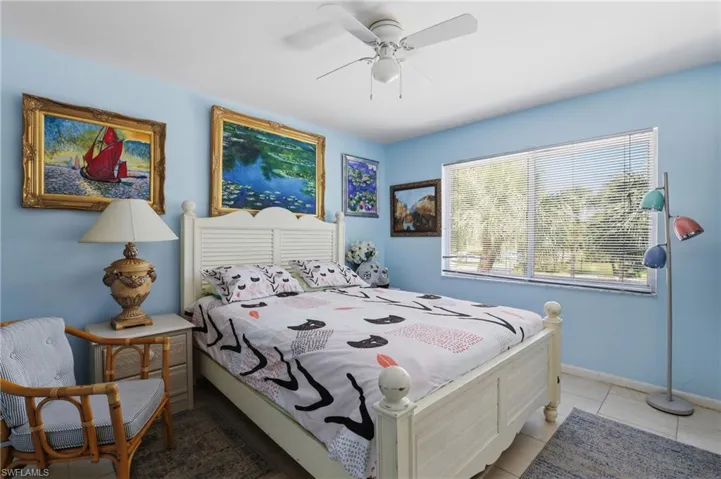Bedroom featuring a white louvered headboard, tiled flooring, and a large window with blinds