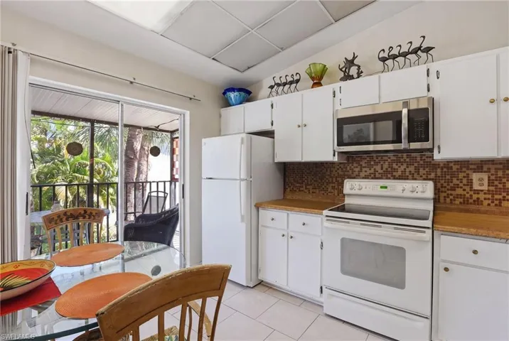 Kitchen featuring white cabinetry, wood-finish countertops, and an integrated stainless steel microwave