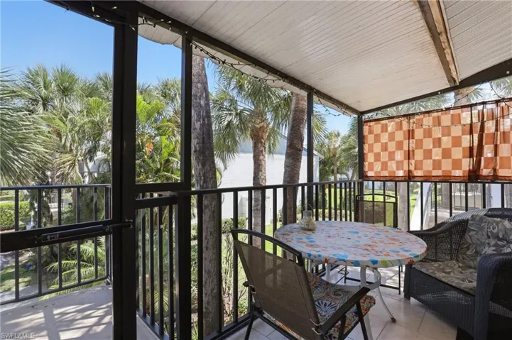 Screened balcony featuring a white corrugated ceiling, dark metal railings, and a partial privacy screen