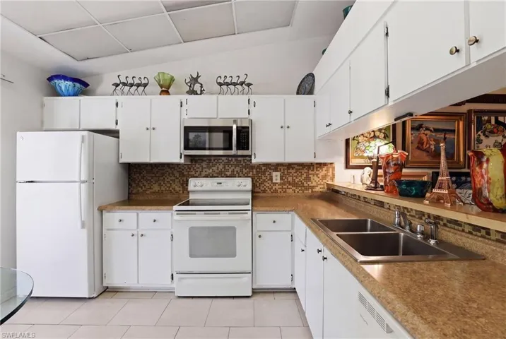 Kitchen featuring white cabinetry, stainless steel sink, built-in microwave, and tile flooring