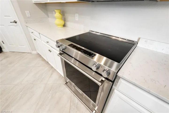 Quartz countertops and stainless steel electric range. Overhead microwave includes air fryer.