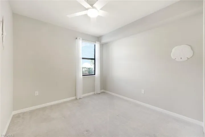 Spare bedroom with ceiling fan and custom closet.